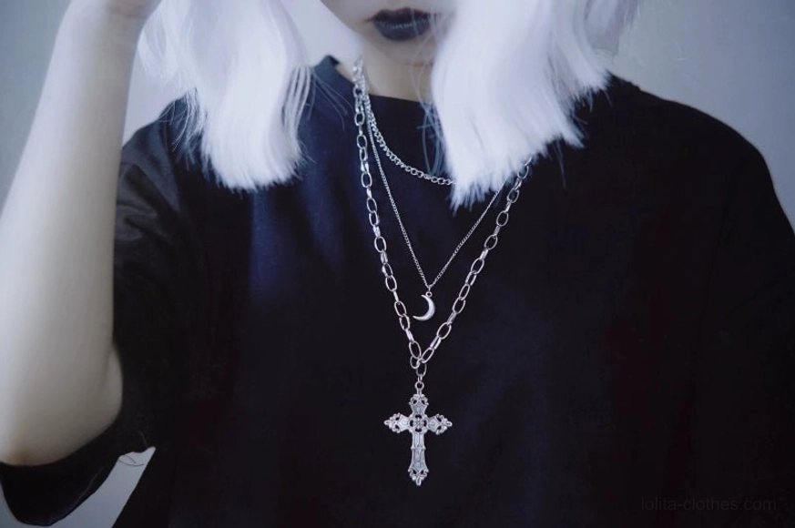 side profile wearing view of gothic lolita triple-layer necklace on model with silver wig and dark top, displaying compact carved cross pendant and matching crescent charm with complete chain set layers