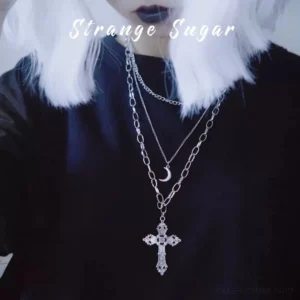 gothic lolita triple-layer cross and moon pendant necklace worn as sweater chain on model with silver wig and black top, showing close-up upper body perspective with carved cross pendant and crescent moon charm details