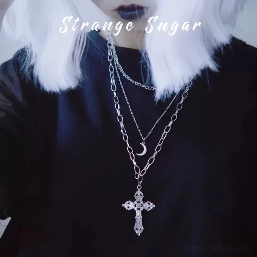 gothic lolita triple-layer cross and moon pendant necklace worn as sweater chain on model with silver wig and black top, showing close-up upper body perspective with carved cross pendant and crescent moon charm details