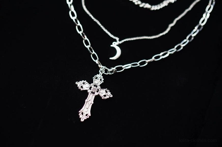 flat lay display of complete gothic lolita triple-layer metal necklace set on black background showing all three distinct chain layers with crescent moon and carved cross pendants in silver tone