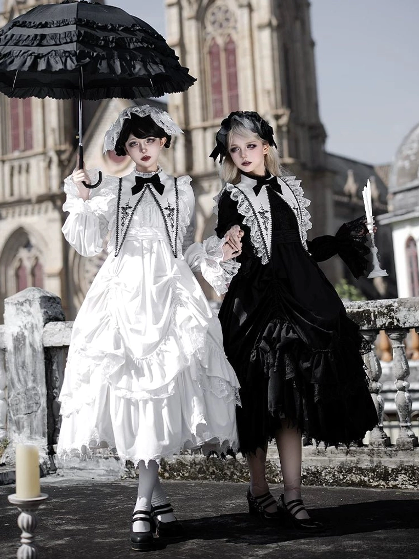 Black and white velvet gothic lolita OP dresses with tiered ruffled skirts, lace-trimmed collars and bow ties photographed on models at cathedral rooftop outdoor location showing front three-quarter view