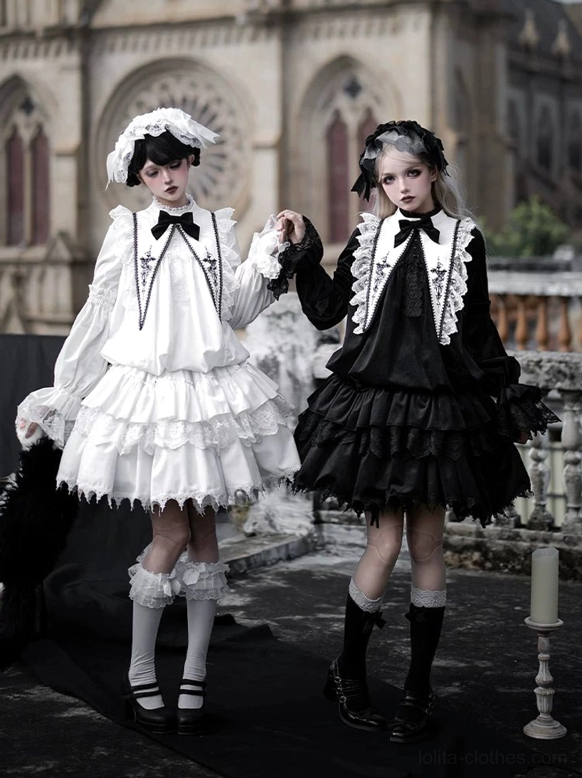 Matching gothic lolita velvet one-piece dresses in black and white with tiered cake skirts, cross-adorned collar straps and matching hair accessories paired with frilled knee socks and leather shoes