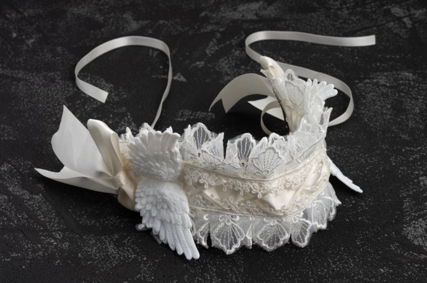 Side profile flat lay of lolita angel wings lace hairband on dark studio background, displaying layered lace structure and adjustable tie strap details