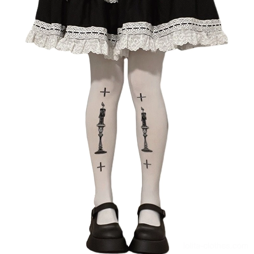 Front straight-on lower leg view of Gothic Lolita white velvet pantyhose with symmetrical black cross and candle prints paired with black platform Mary Jane shoes