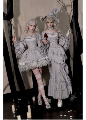 Gray Gothic witch lolita dress suit with structured bodice cowl neckline and voluminous skirt worn by two models holding magical props in atmospheric candlelit setting