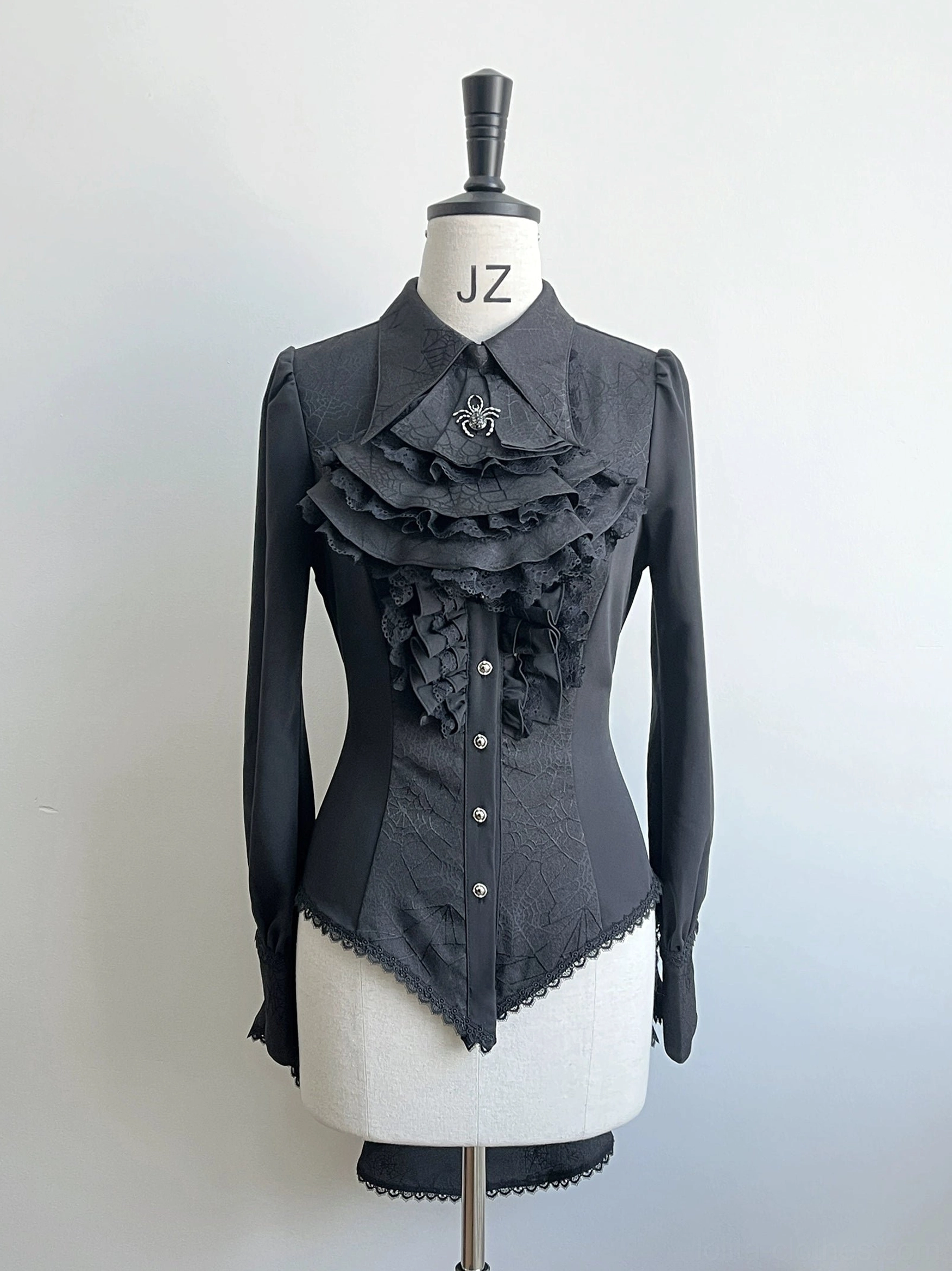 Black gothic Ouji lolita shirt with spiderweb jacquard pattern displayed on dress form front view showing ruffled lace placket and pearl button closures