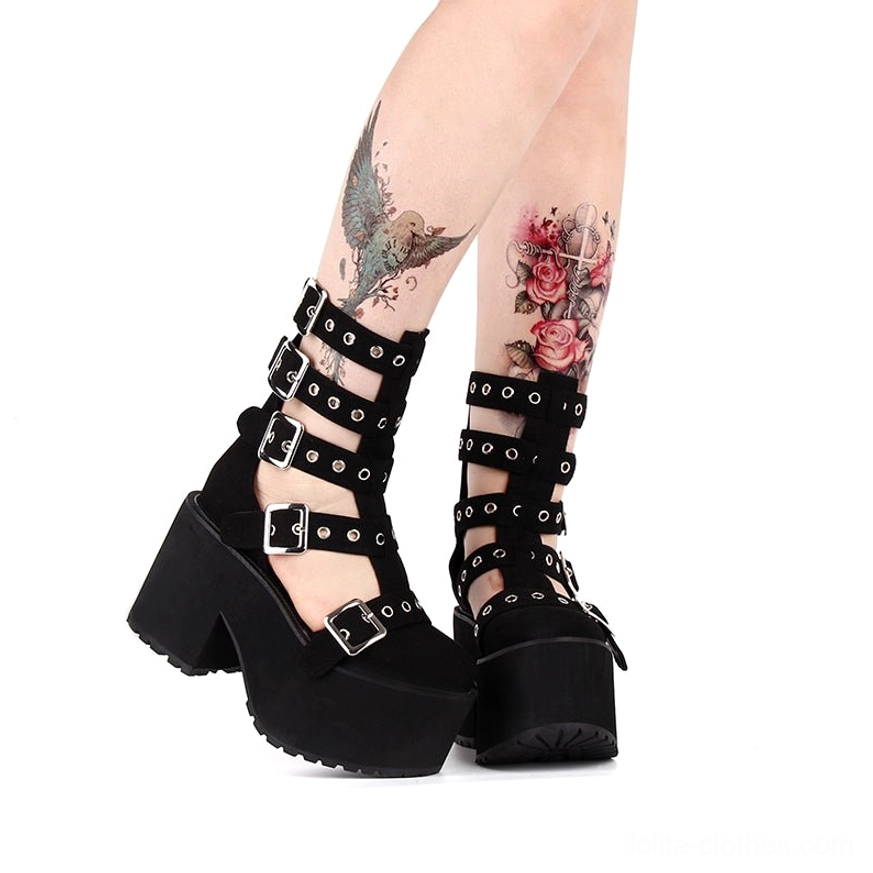 Side view of tattooed model leg wearing platform gladiator boots, highlighting multi-layer eyelet buckle straps, thick block platform heel, and sleek patent leather upper