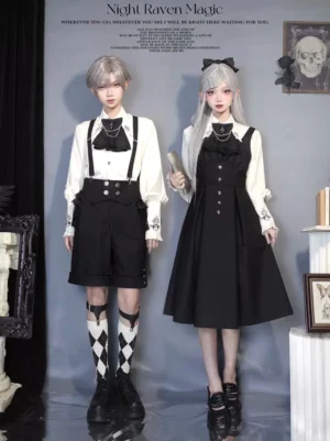 Night Raven Magic Ouji Lolita couple dress set featuring black and white color scheme with full front view of male and female models in gothic studio setting, showcasing suspender shorts and long jumper dress with matching long-sleeve blouses