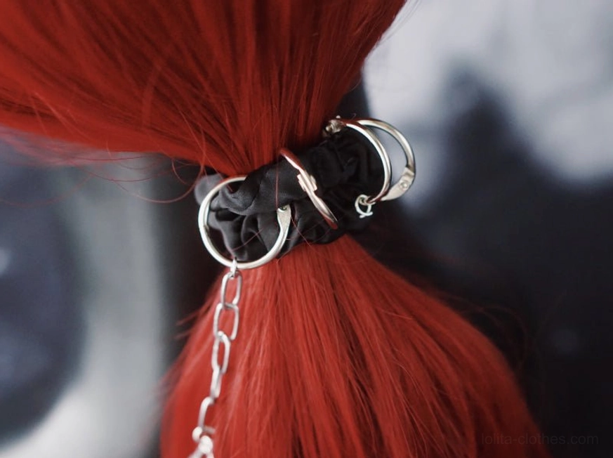 Chain-style goth hairband on red ponytail showing metal hardware and skull attachments