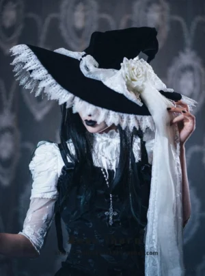 Gothic lolita witch hat with detachable rose headdress worn on model with black velvet body and white lace trim, paired with gothic lolita dress and cross pendant necklace against vintage patterned background