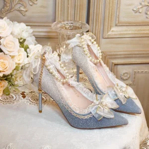 Gradient silver-blue glitter wedding lolita high heel shoes with pearl chains, pointed stiletto heel, ruffled lace and sheer bow embellishments displayed on European retro-style table with white flowers