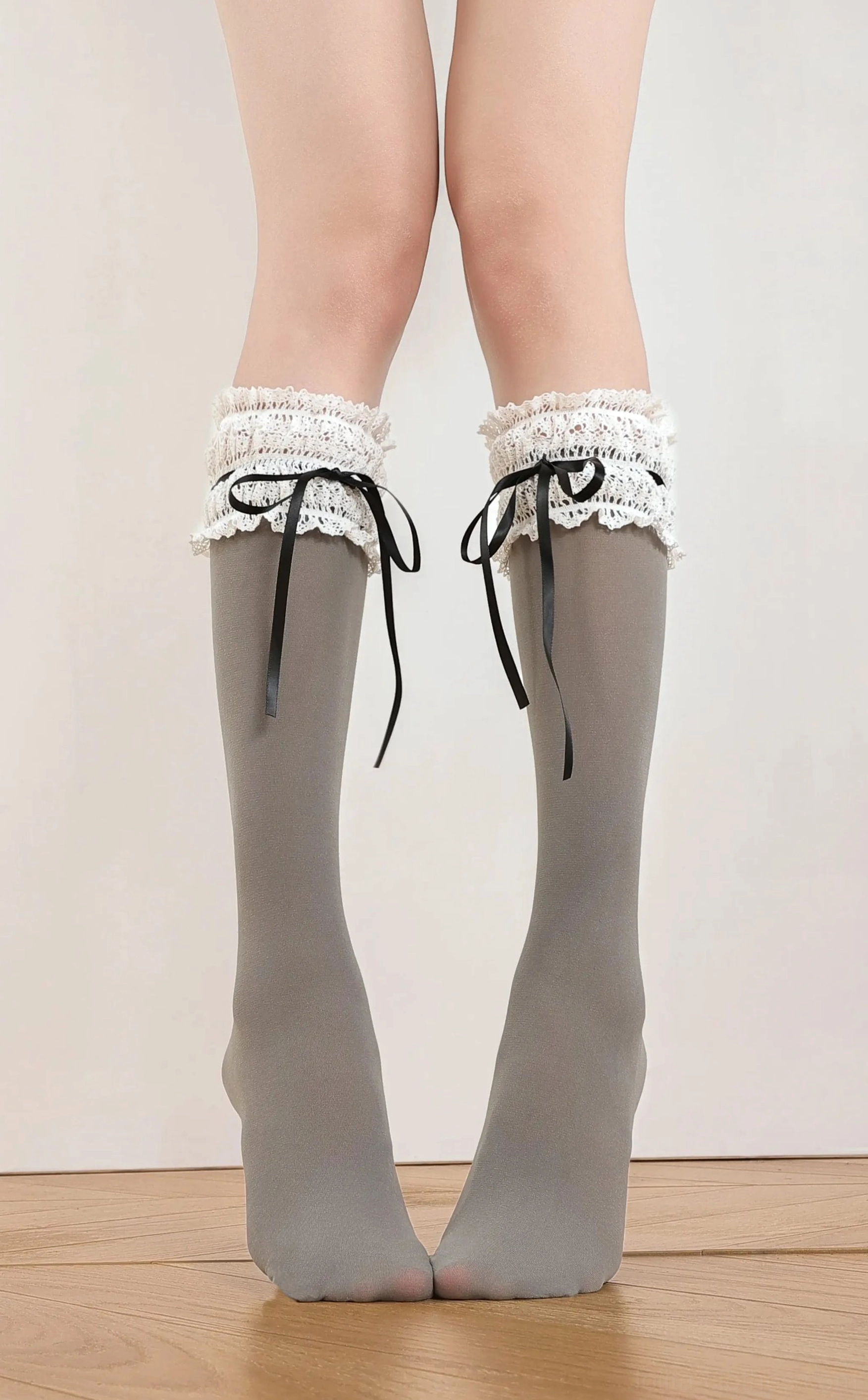 Gray calf-length classic lolita ruffle socks with frilled lace cuff and satin ribbon bow detail, neutral color front view