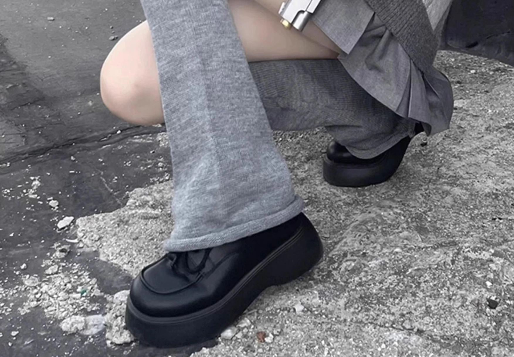 Gray ribbed lolita leg warmers close-up crouching side view outdoor concrete showing flared hem and soft knit material texture