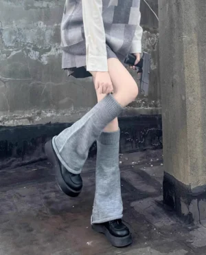 Gray ribbed knit mid-calf lolita leg warmers styled with checkered long-sleeve top pleated mini skirt and platform loafers low side view