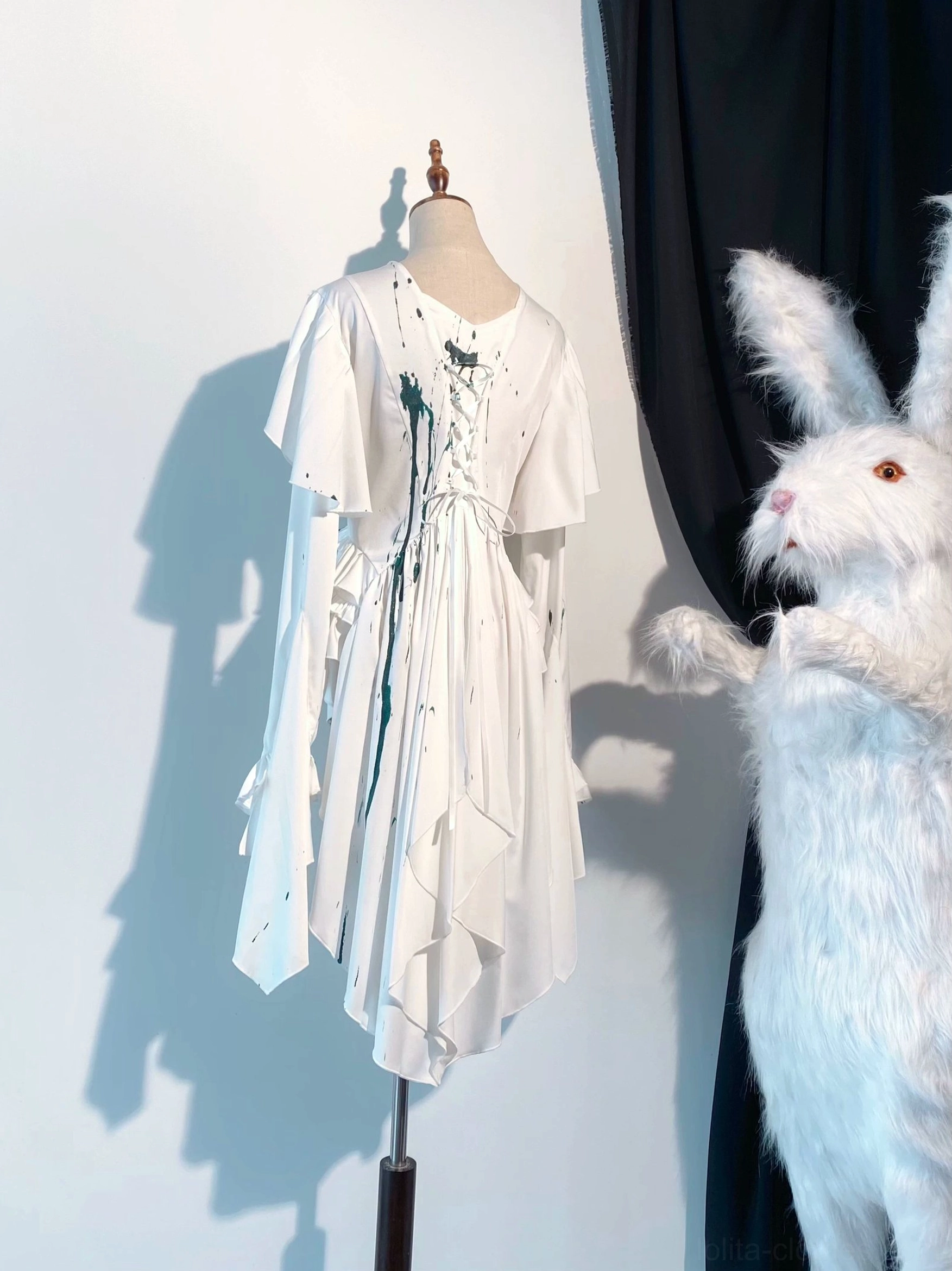 Green blood-stain Ouji lolita trailing blouse with lace-up front detail and long trailing hem, white satin fabric with emerald splash prints, full front mannequin display with gothic aesthetic