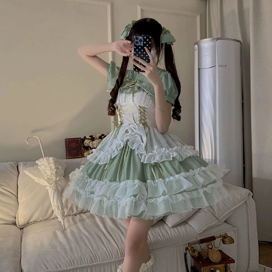 Close-up detail of sage green lolita wedding JSK showing hand-sewn ribbon bows at bodice, decorative stitching, and three complimentary bow accessories included with dress