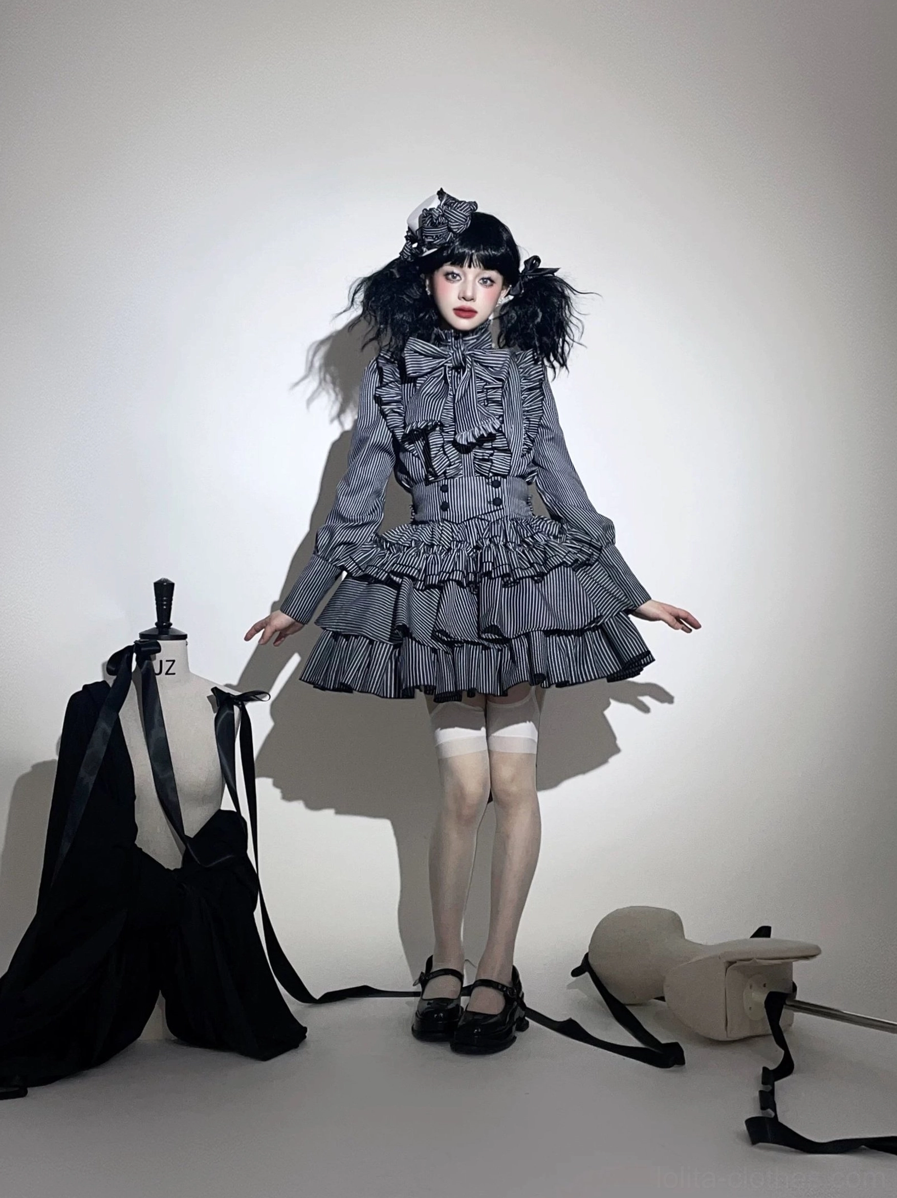 Grey striped gothic lolita set worn by model in medium standing front perspective, showing fitted ruffled bodice, stripe pattern fabric, and coordinating hair accessory