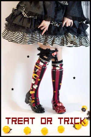 Gothic Lolita Halloween red striped bat pumpkin knee-high socks worn by model in black ruffled lolita dress with yellow string lights decoration