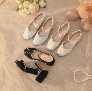 Han Lolita chunky heel shoes flat lay display featuring black and light blue variants with embroidered details pearl ankle strap and square toe floral applique on linen background with teddy bear and roses