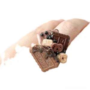 Handcrafted chocolate cookie adjustable ring worn on finger with miniature biscuit, cream swirl, pretzel, and dark chocolate bead details for Sweet Lolita fashion