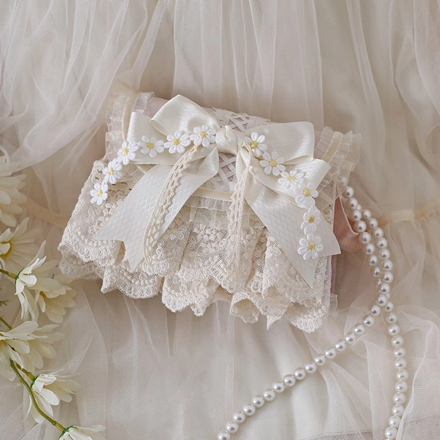 Handmade ivory lace lolita bag with embroidered daisy satin bow, top oblique view against tulle backdrop with white flowers