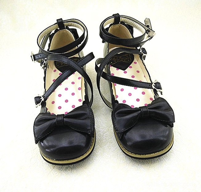 Handcrafted Lolita low heel princess shoes with signature cross ankle buckle straps, decorative bow accent, and kawaii polka dot lining detail, sweet Lolita aesthetic footwear