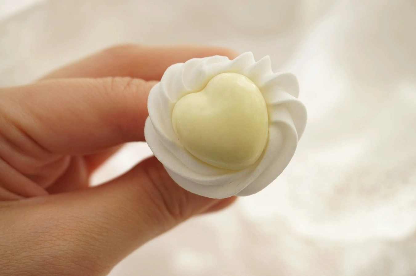Yellow handmade cream heart adjustable Lolita ring held between fingers showing sculpted heart statement design