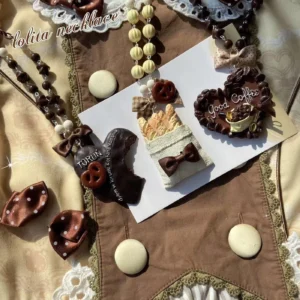 Handmade resin dessert themed lolita necklaces collection flat lay featuring brown beaded chains polka dot bows chocolate pretzel heart shaped pendants retro lolita style fabric background