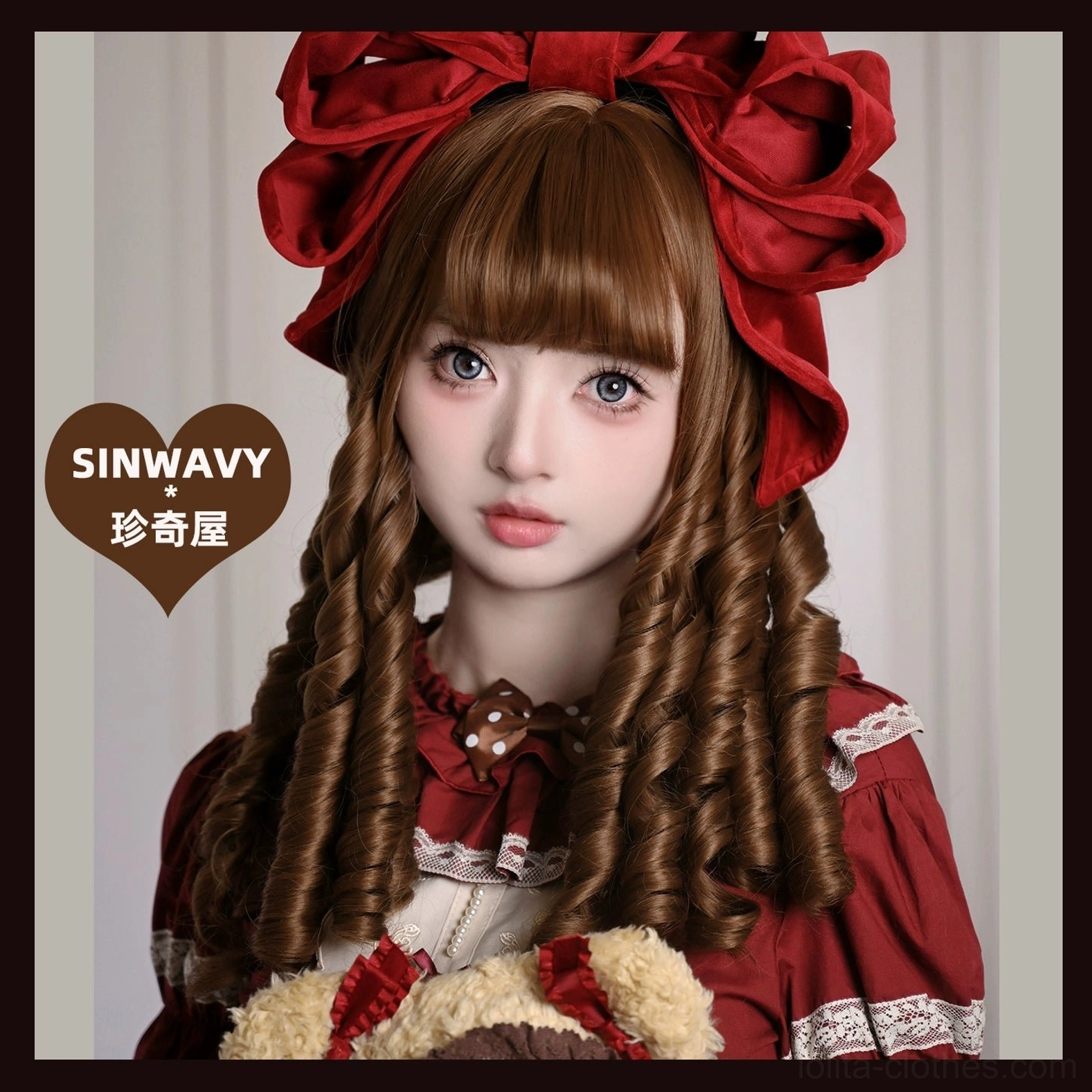 Human model wearing honey brown roman curl lolita wig with straight bangs, big red bow, and coordinating red lolita dress in neutral indoor setting