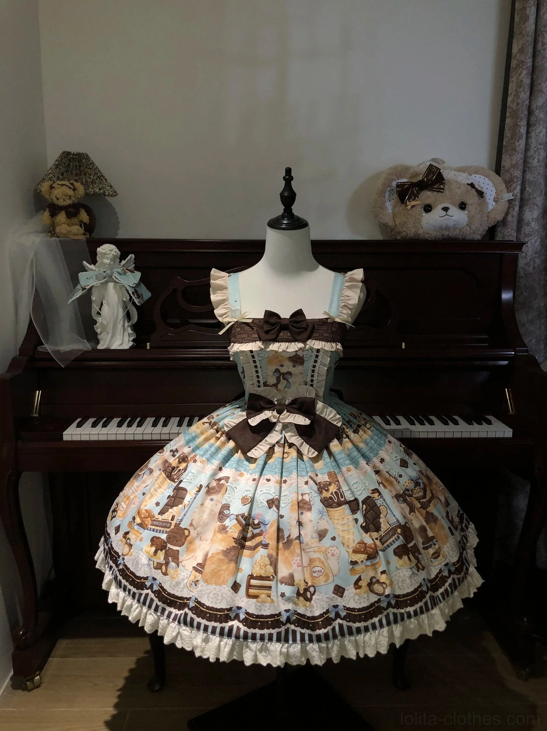 Mint green Honey Chocolate Lolita JSK dress on mannequin displaying square neckline, fixed waist bow, allover dessert and cat print, ruffled shoulder straps, and refined sweet lolita silhouette in piano room