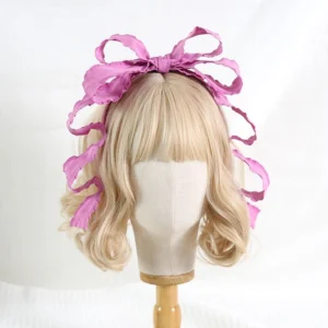 Hot pink ruffled satin bowknot Lolita KC hair accessory with long trailing ribbons displayed on blonde wig mannequin