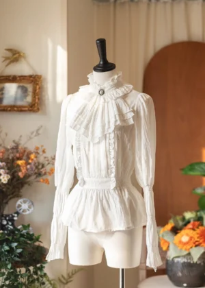 Classic ivory lolita long sleeve blouse with detachable ruffled jabot collar displayed on dress mannequin, featuring pleated front panel and lantern sleeves against vintage floral decor backdrop