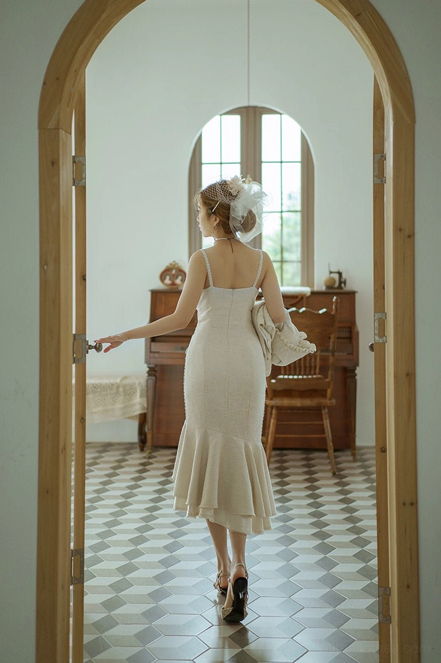 Ivory fishtail slip Lolita dress with low back design and slim midi silhouette, back full-body view in retro piano hallway, demonstrating elegant trailing fishtail hem