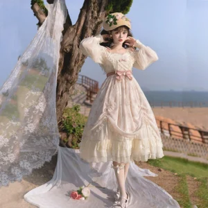Ivory floral princess lolita OP dress front three-quarter view with cream base color, pink waist bow, ruffled square neckline, sheer puff sleeves, outdoor seaside setting with lace backdrop and model wearing floral straw hat white stockings