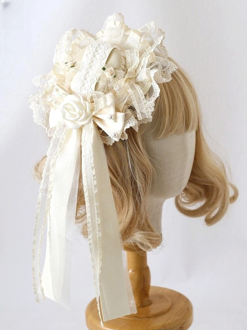 Ivory lace lolita headdress with ruffled lace, satin bows and fabric roses displayed on blonde wig mannequin - side three-quarter view showing Victorian aesthetic