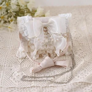 Ivory sweet lolita tea party handbag with pink handle and large satin bow displayed on vintage lace with daisy flowers flat lay