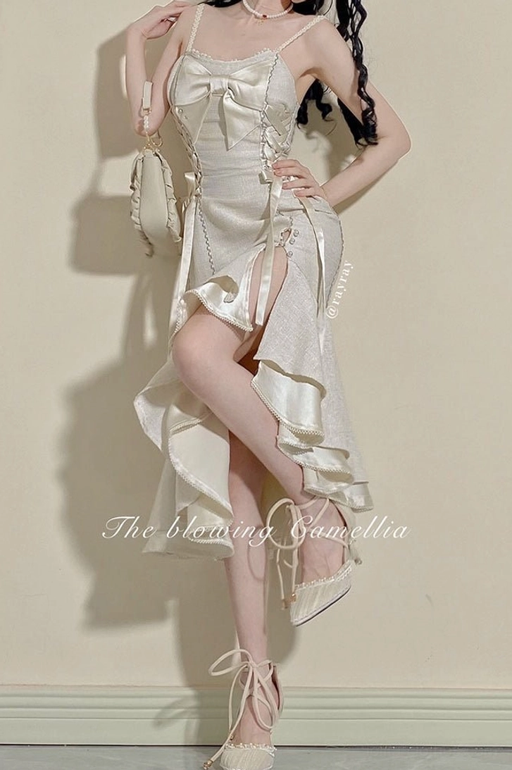Ivory satin fishtail Lolita dress with lace-up bust design, high side slit and shiny satin fabric, ruffled fishtail hem posed against minimalist indoor wall background