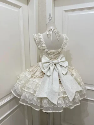 Rear view of ivory sweet lolita jumper skirt displaying oversized satin back bow, halter neck tie, and multi-tiered lace ruffled petal skirt layers on dress form