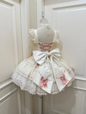 Back view of ivory sweet lolita JSK with large detachable bow and ruffled tiered skirt hem on dress form