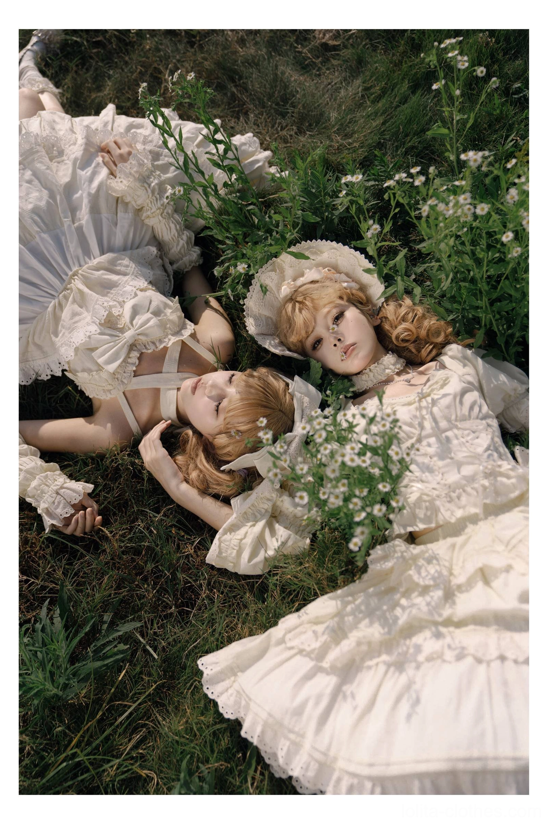 Ivory white sweet lolita one-piece dresses with lace-trimmed tiered skirts, matching bonnet hats, romantic vintage styling, worn by two models lying on grass with flower props
