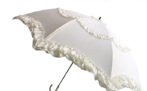 Ivory white Lolita parasol with delicate ruffled lace edging and elegant curved metal handle shown from front oblique angle