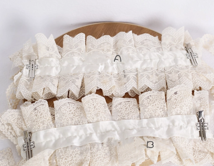 Labeled lolita lace headdress parts flat lay top-down view with A and B style tags, showing metal spring clips, satin ribbon bands, and floral lace material variations comparison