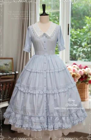 Dusty light blue Lolita OP dress with button-front closure and intricate lace detailing, showcasing full-length tiered ruffle skirt vintage studio setting