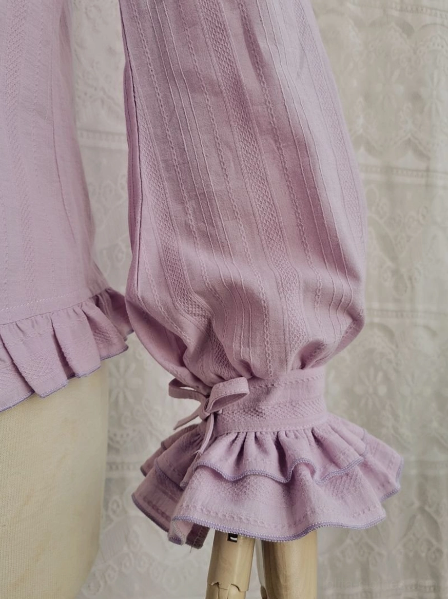 Side close-up view lavender purple cotton Lolita blouse ruffled cuff fabric bow consistent stripe texture embroidered fabric backdrop detail shot