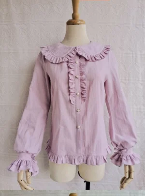 Lavender purple cotton Lolita blouse with ruffled Peter Pan collar pearl button fasteners and ruffled cuffs hem on dress form embroidered backdrop