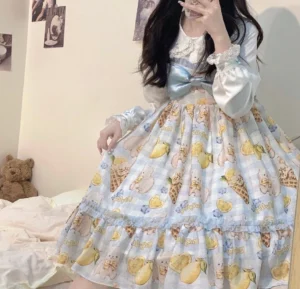 Lemon bear dessert print lolita jumper skirt dress side three-quarter view showing tiered ruffled hem and blue plaid base fabric on seated model