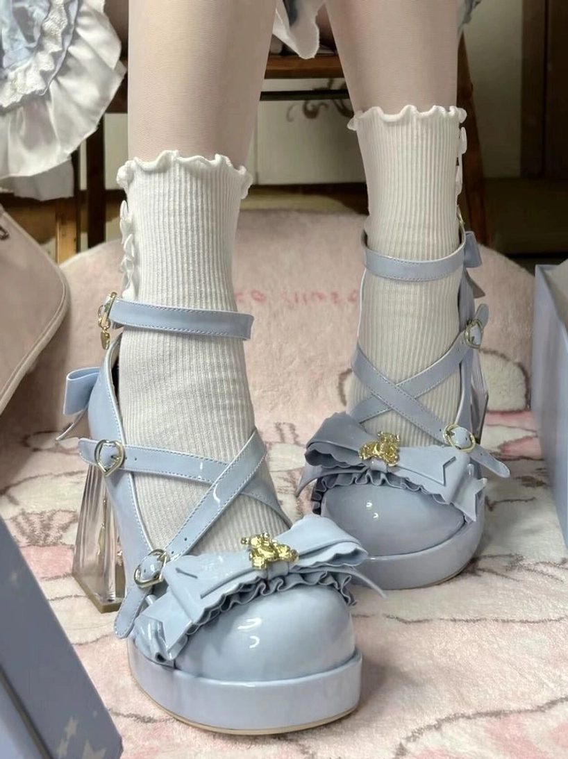 Light blue sweet lolita platform heels with transparent block heel featuring embedded bear charm, worn with white ruffled ankle socks, crisscross ankle strap, patent leather finish, gold bear decoration on ruffled bow