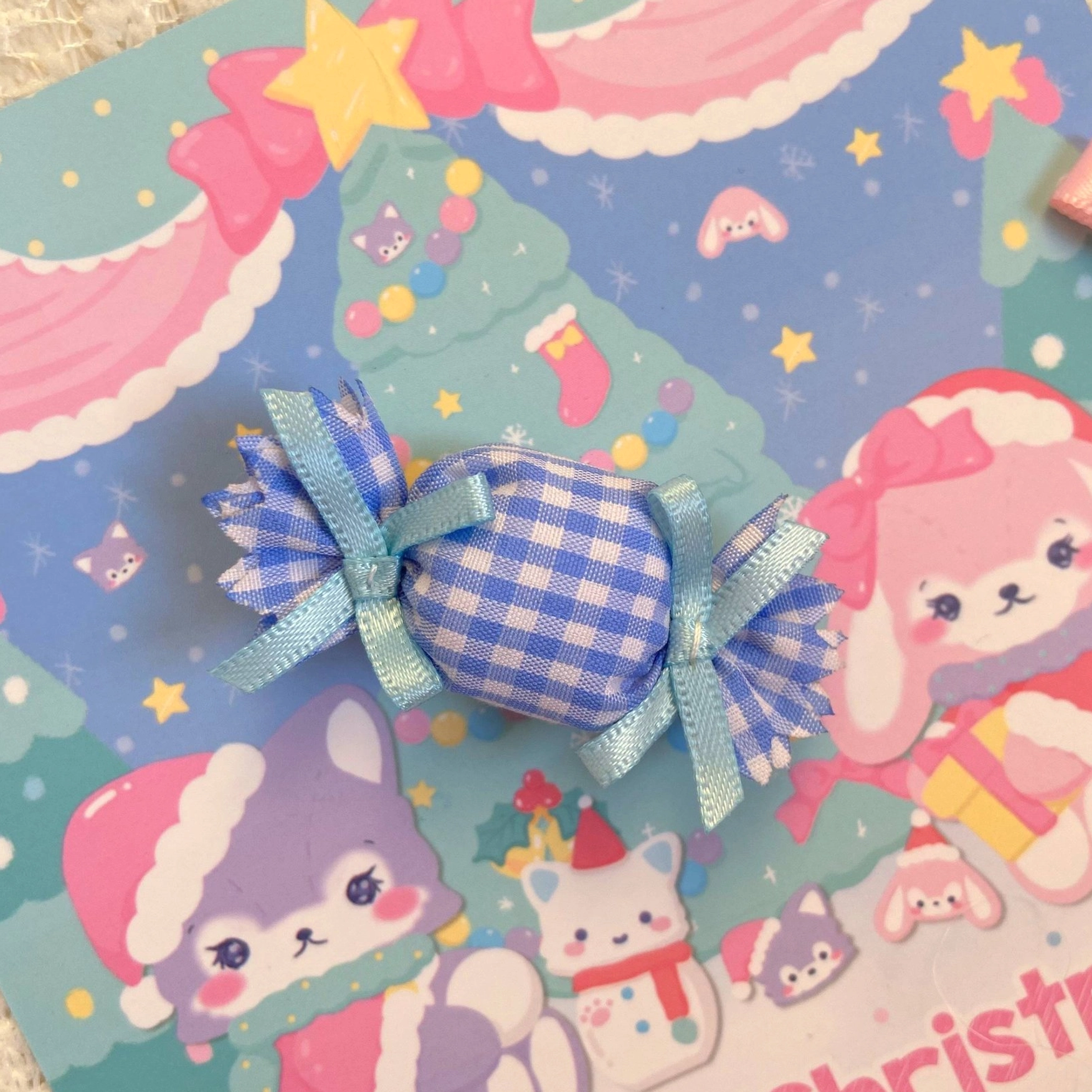 Light blue gingham candy lolita hair clip with checkered fabric pattern and blue ribbon bows on kawaii Christmas background, headdress accessory detail