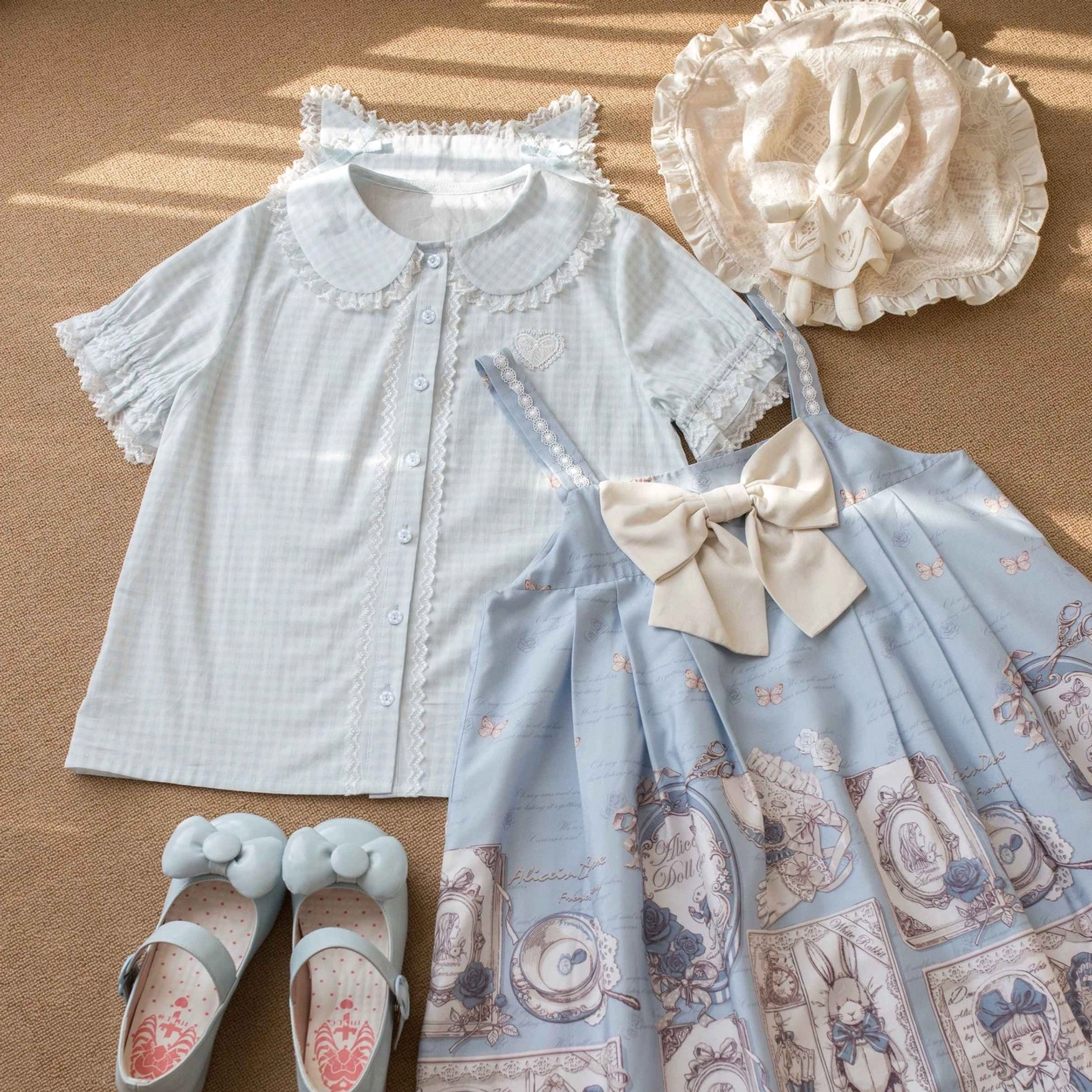 Light blue gingham plaid Lolita short-sleeve blouse with cat ear Peter Pan collar and lace trim, displayed in flat lay with blue print jumperskirt, baby bonnet and leather shoes