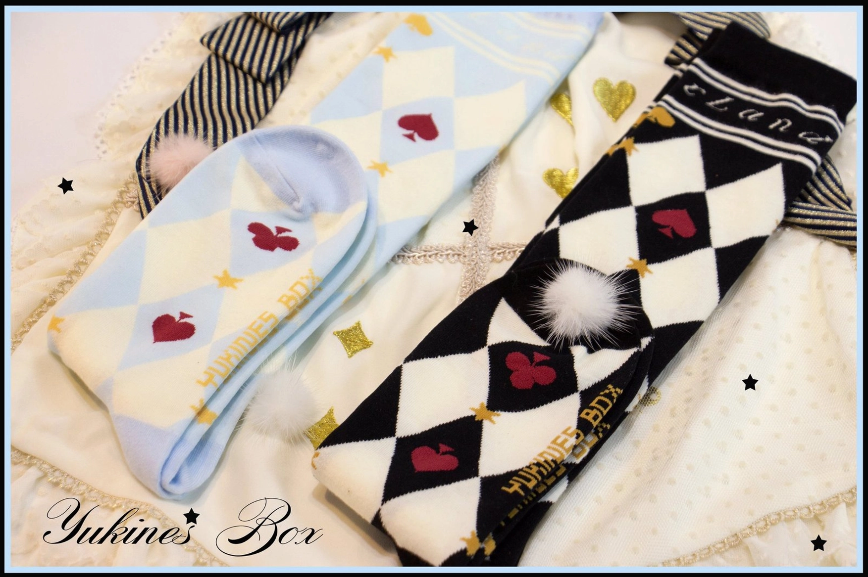 Light blue heart poker print and black checkerboard fuzzy pom-pom asymmetrical lolita cotton socks close up flat lay star fabric background